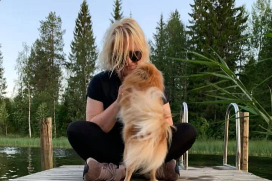 Johanna sitter på en brygg med sin älskade hund i famnen