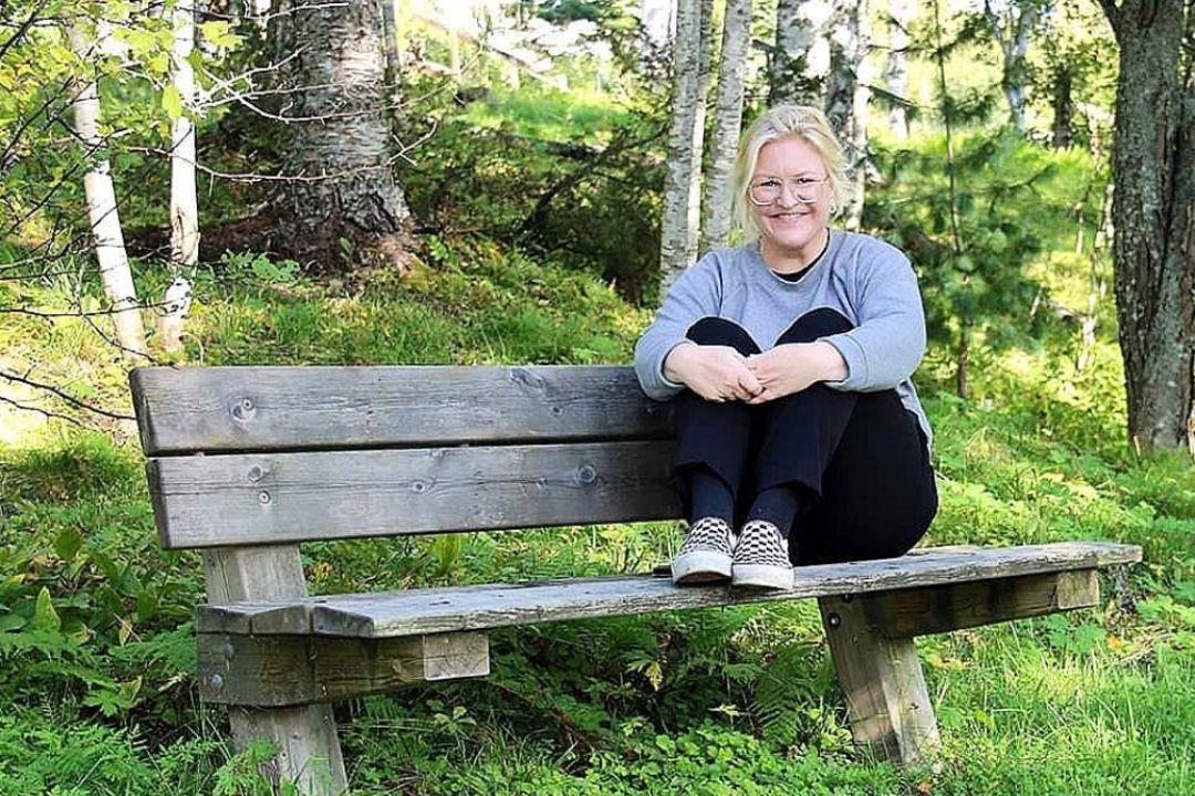 Johanna sitter på en bänk i en grönskande skog