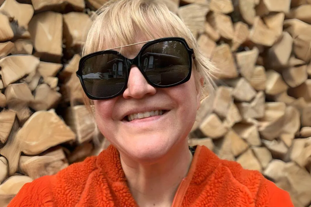 Johanna med solglasögon framför ett rappsfält.
