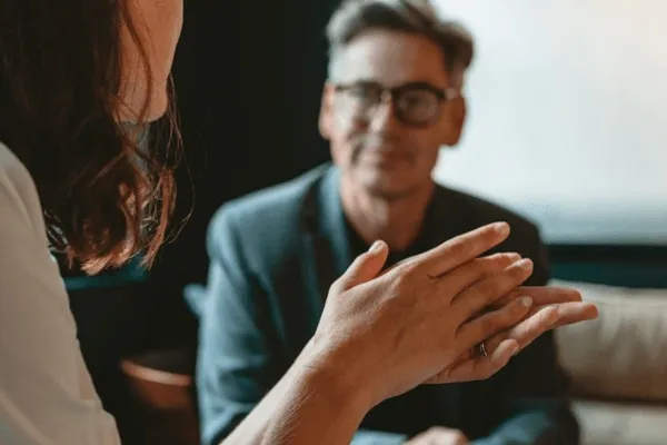 woman gestures while talking to seated man