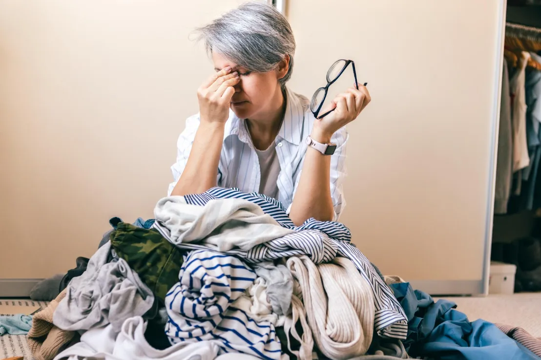 Midlife woman standing in front of a closet full of clothes feeling frustrated and unsure what to wear