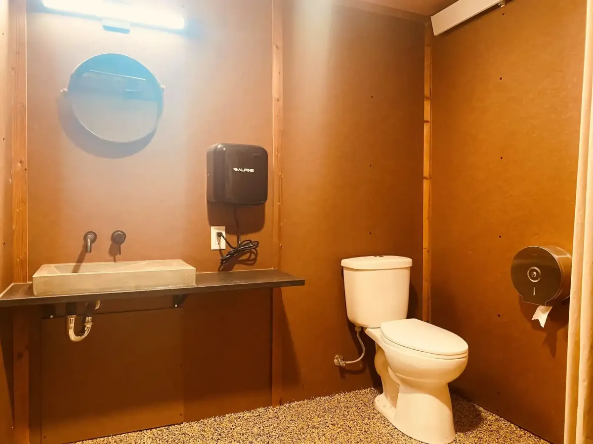 Modern campground bathroom at SOBO's Campground featuring a concrete vessel sink, large mirror, hand dryer, and spacious private restroom.