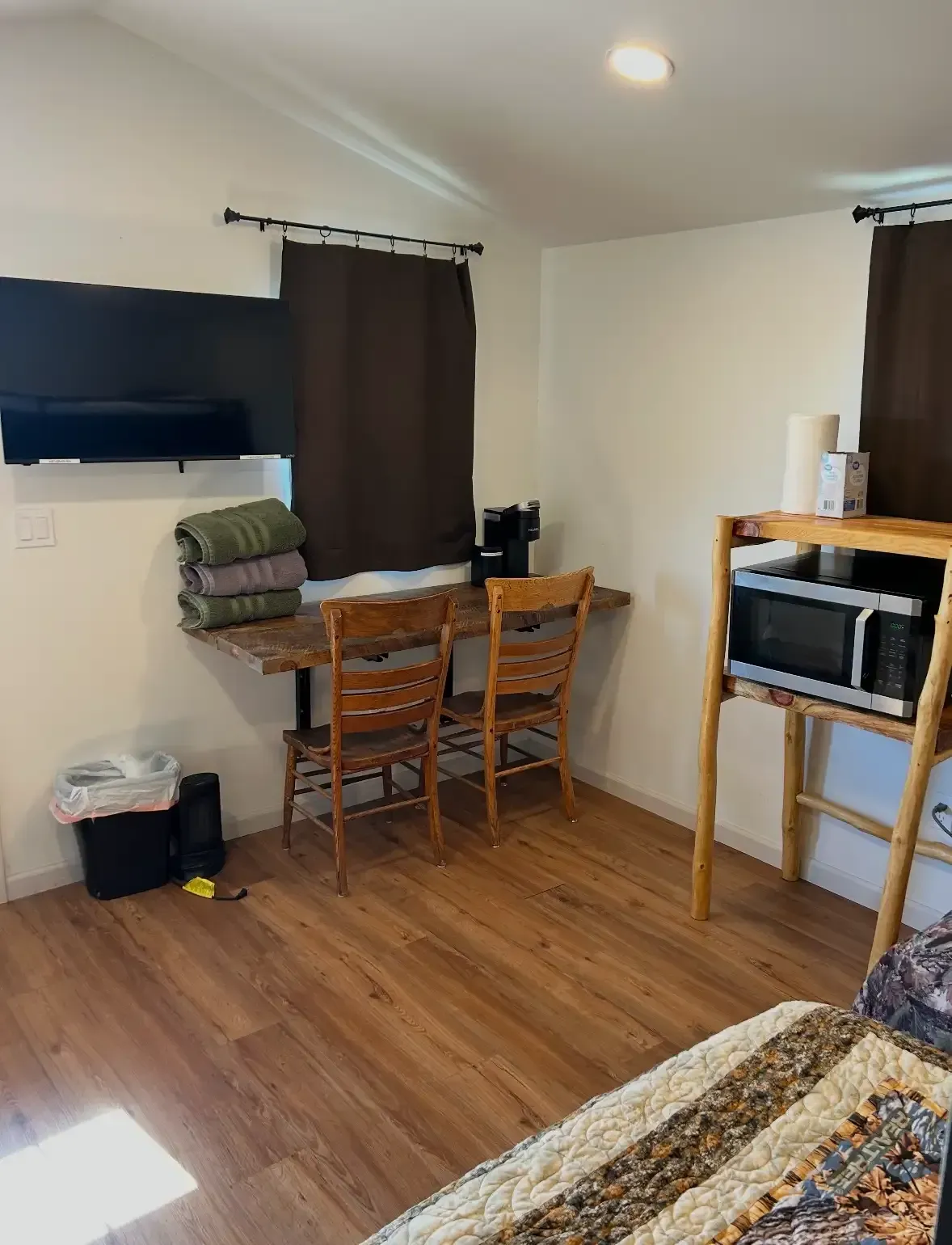 Inside a modern cabin at SOBO's Campground featuring a bunk bed, television, coffee station, microwave, mini refrigerator, and rustic furnishings.