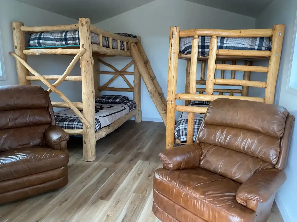 Rustic family cabin interior at SOBO's Campground featuring handcrafted log bunk beds, leather recliners, and spacious accommodations.