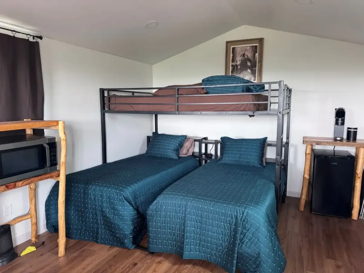 Comfortable bunk bed setup inside a SOBO's Campground cabin with modern bedding, coffee station, mini fridge, and relaxing accommodations.