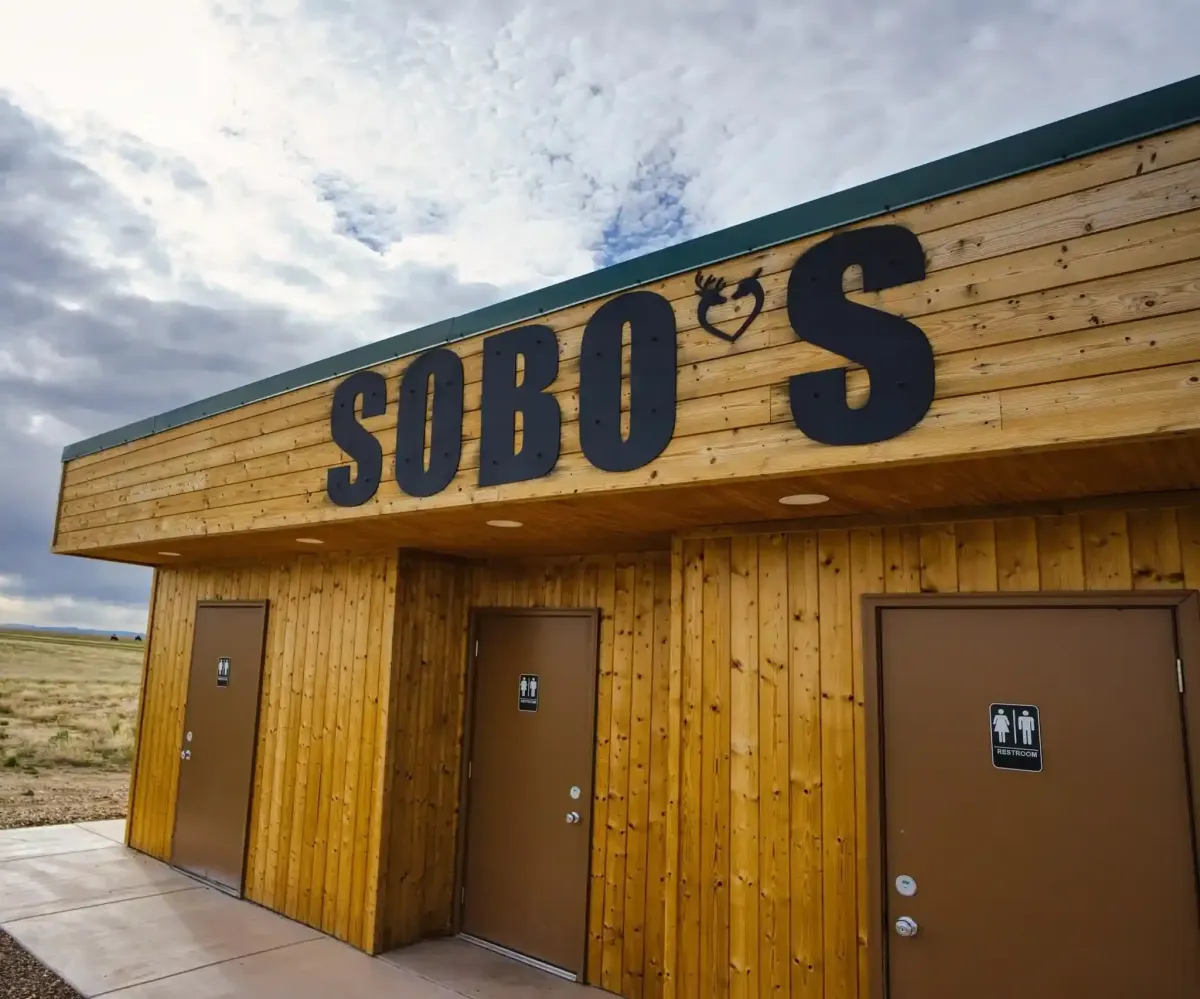 Exterior of the SOBO's Campground bathhouse with modern private restrooms, showers, and rustic wood construction in Scenic, South Dakota.