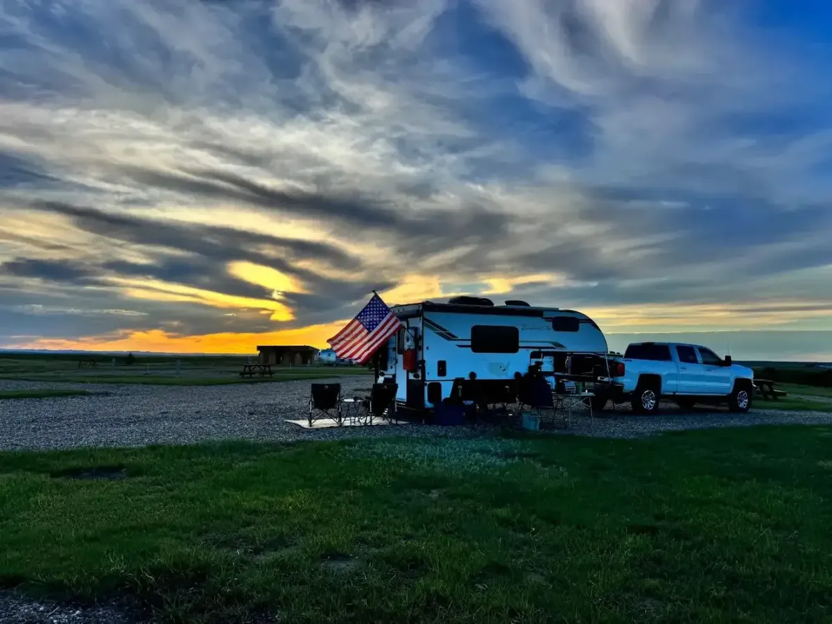 RV camping with an American flag flying beneath colorful South Dakota evening skies at SOBO's Campground.