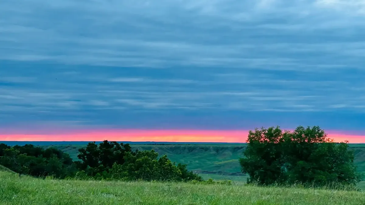 Vibrant pink sunset stretching across the Badlands horizon from SOBO's Campground.