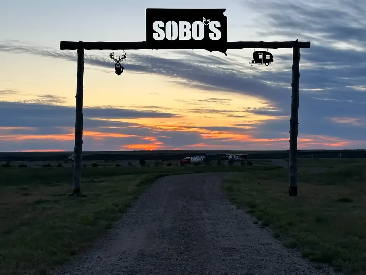 Entrance sign welcoming guests to SOBO's Campground during a colorful South Dakota sunset.