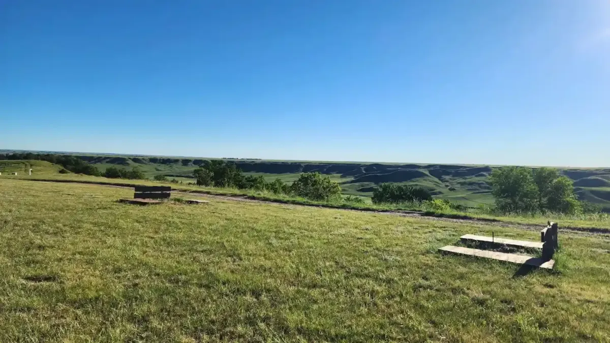 Scenic overlook of the Badlands valley with grassy hills and campground seating at SOBO's Campground in Scenic, South Dakota.