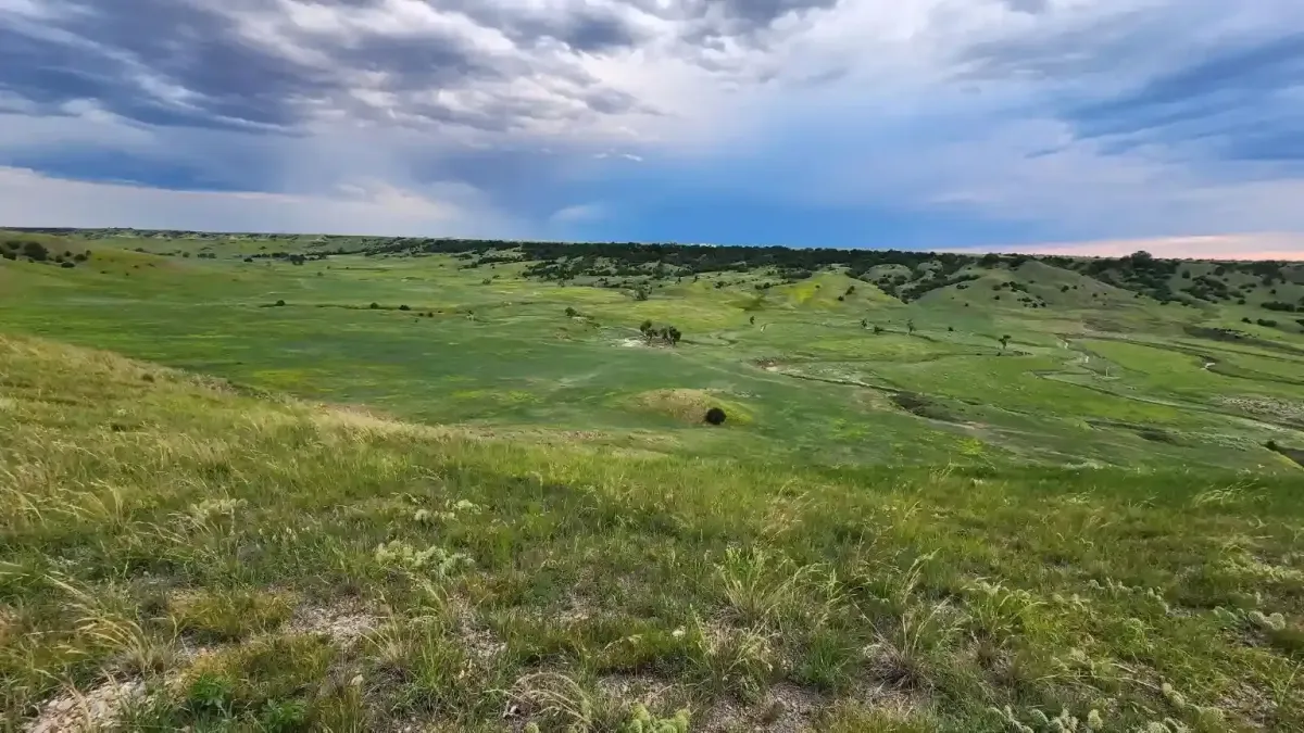 Panoramic view of the rolling green prairie and dramatic storm clouds overlooking the Badlands from SOBO's Campground in Scenic, South Dakota.