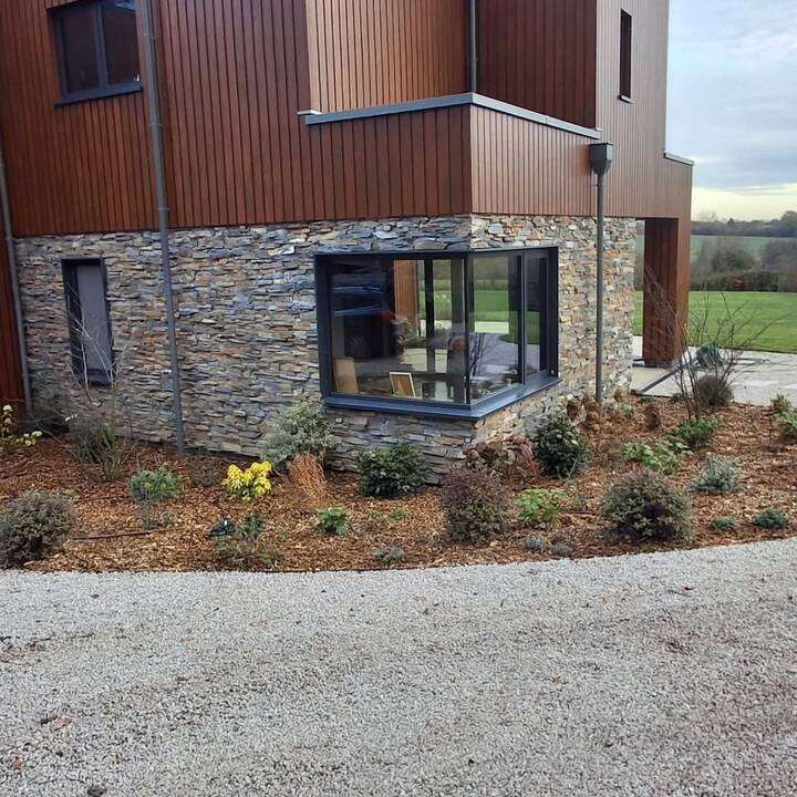 Premium grey porcelain patio installation alongside modern home with topiary border in Chiswick