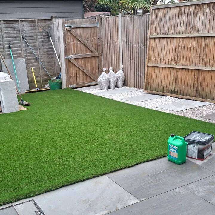 Sunlit artificial grass lawn next to modern patio and bi-fold doors in Beaconsfield
