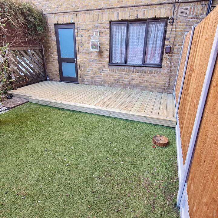 Family garden with artificial grass lawn, trampoline, and paver patio in Ruislip