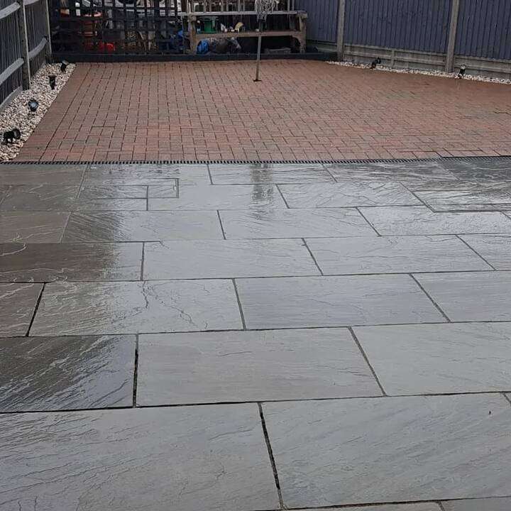Wet-look slate patio installation with timber pergola post and rear garden border in Fulham