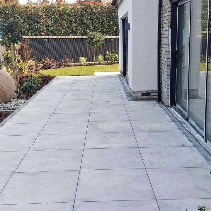 Completed garden design and landscaping project with raised planters, lawn, and feature bench in West London