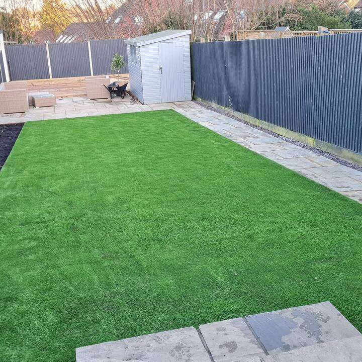 Grey porcelain patio installation alongside white conservatory with garden furniture set in Ealing