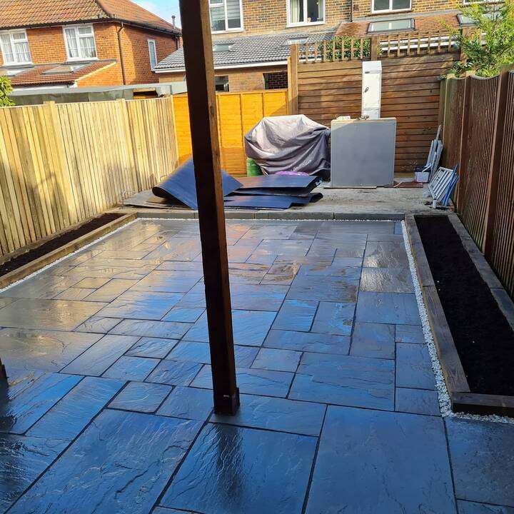 Light cream porcelain patio installation against modern home with bi-fold doors in Holland Park