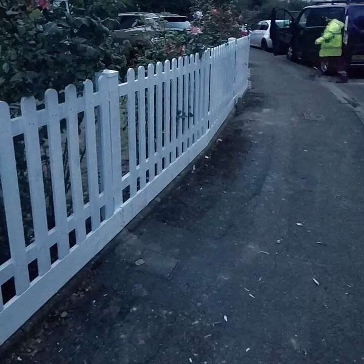 Side view of a white picket fence running along a front garden path