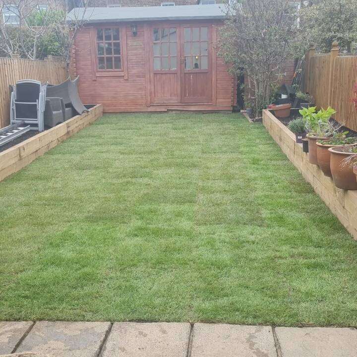 Compact urban garden corner with artificial grass and pebble border in Holland Park