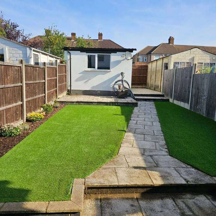 Garden with timber sleeper raised beds and timber garden room at the rear in Pinner