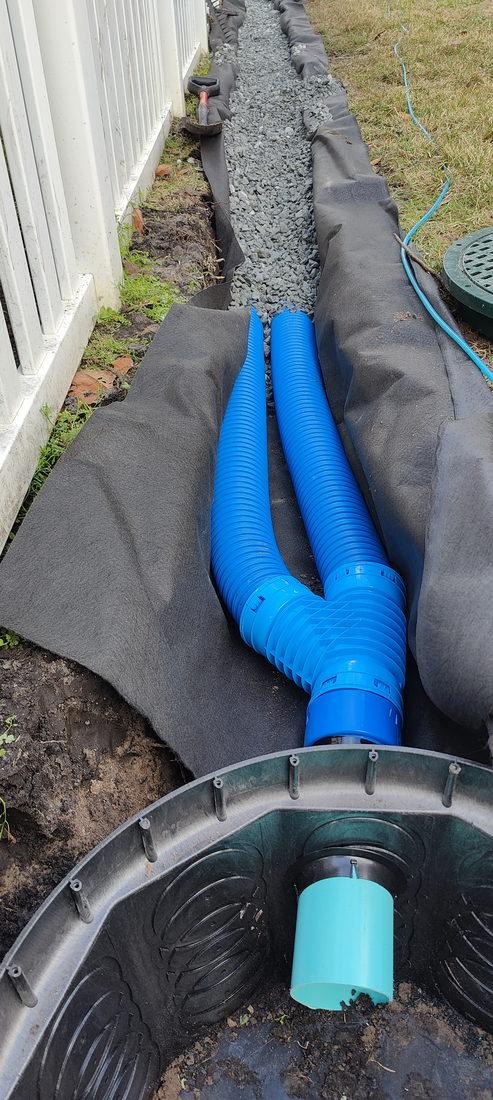 Two four-inch perforated pipes side by side in a fabric-lined French drain trench