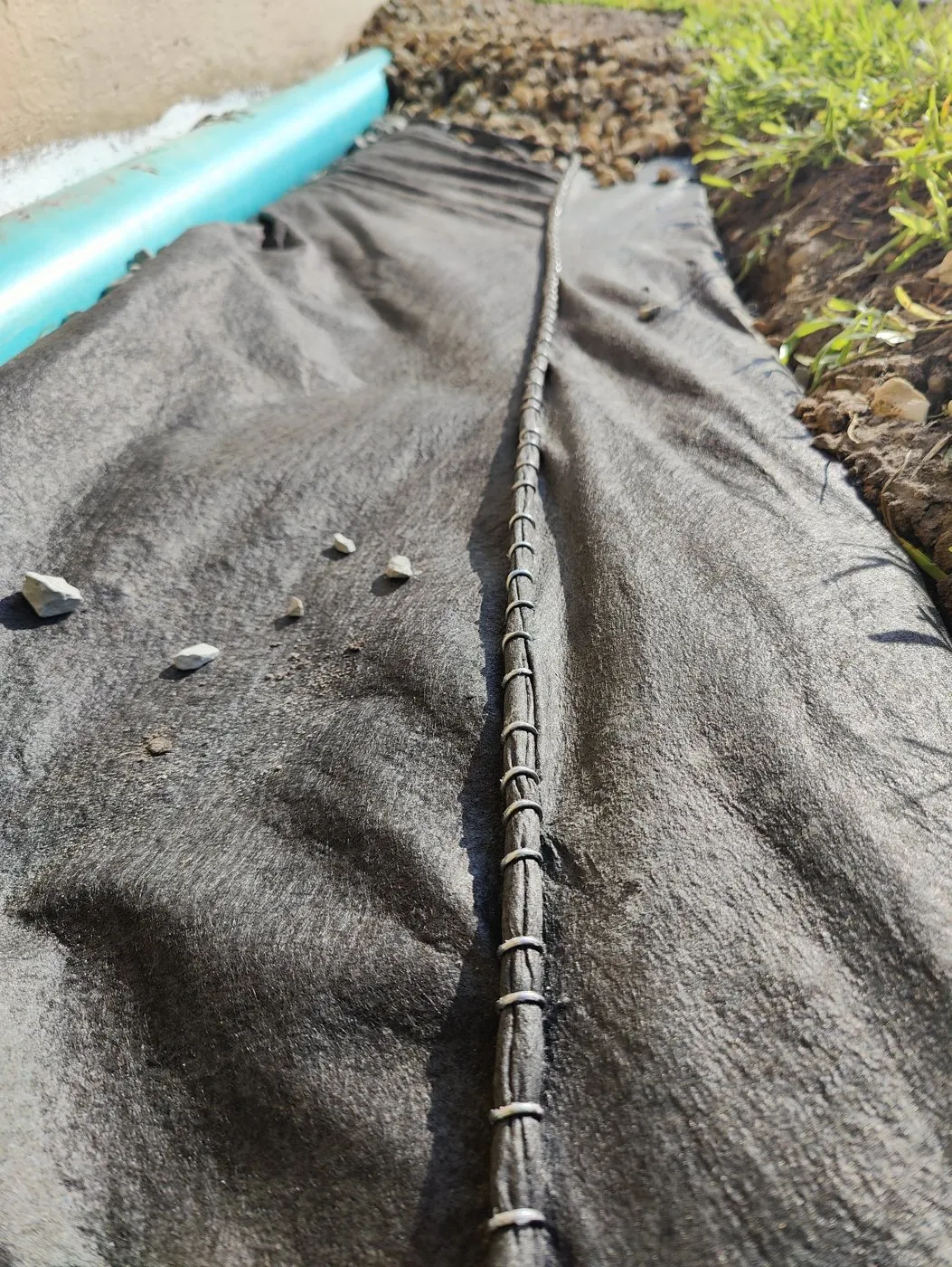 Foundation drain wrapped in fabric and stapled closed with the downspout tied in