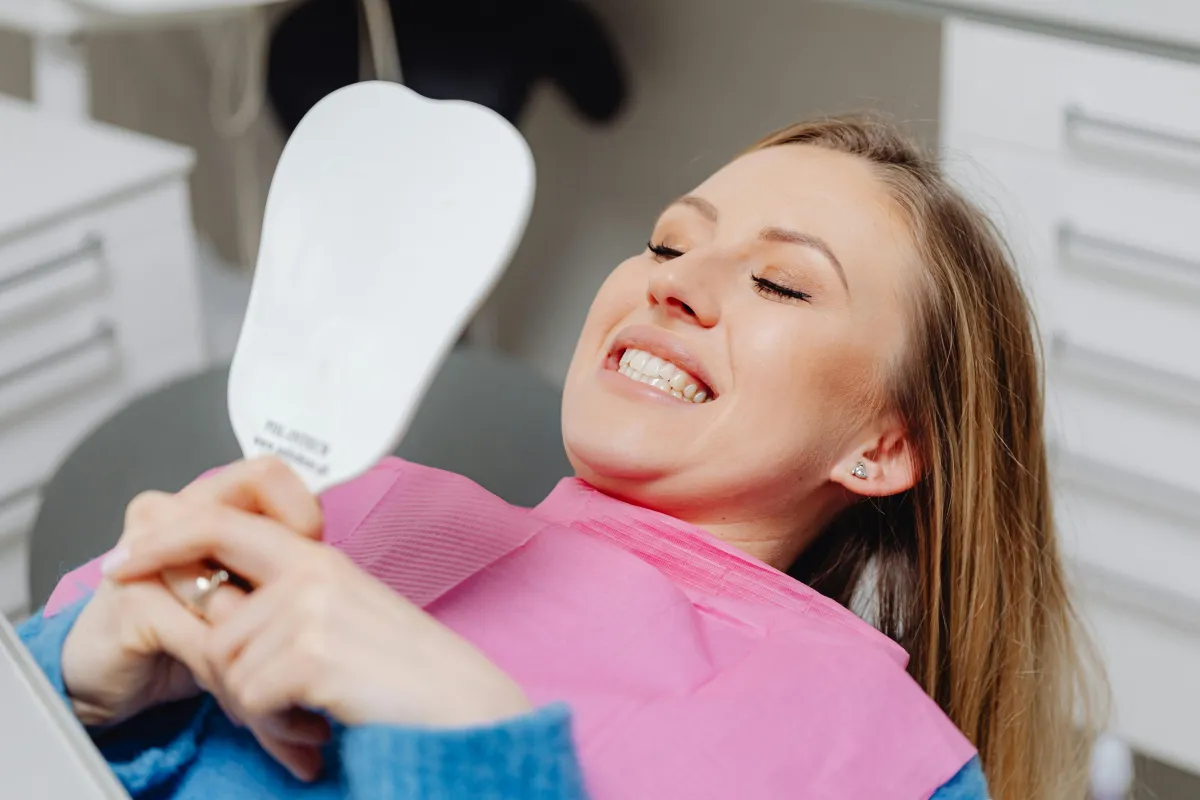 Girl in dentist chair smiling while looking at her teeth