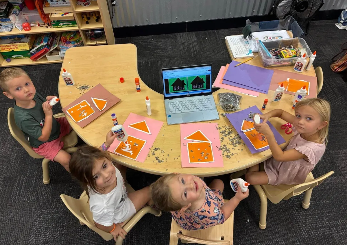 Preschoolers gluing house drawings around a table