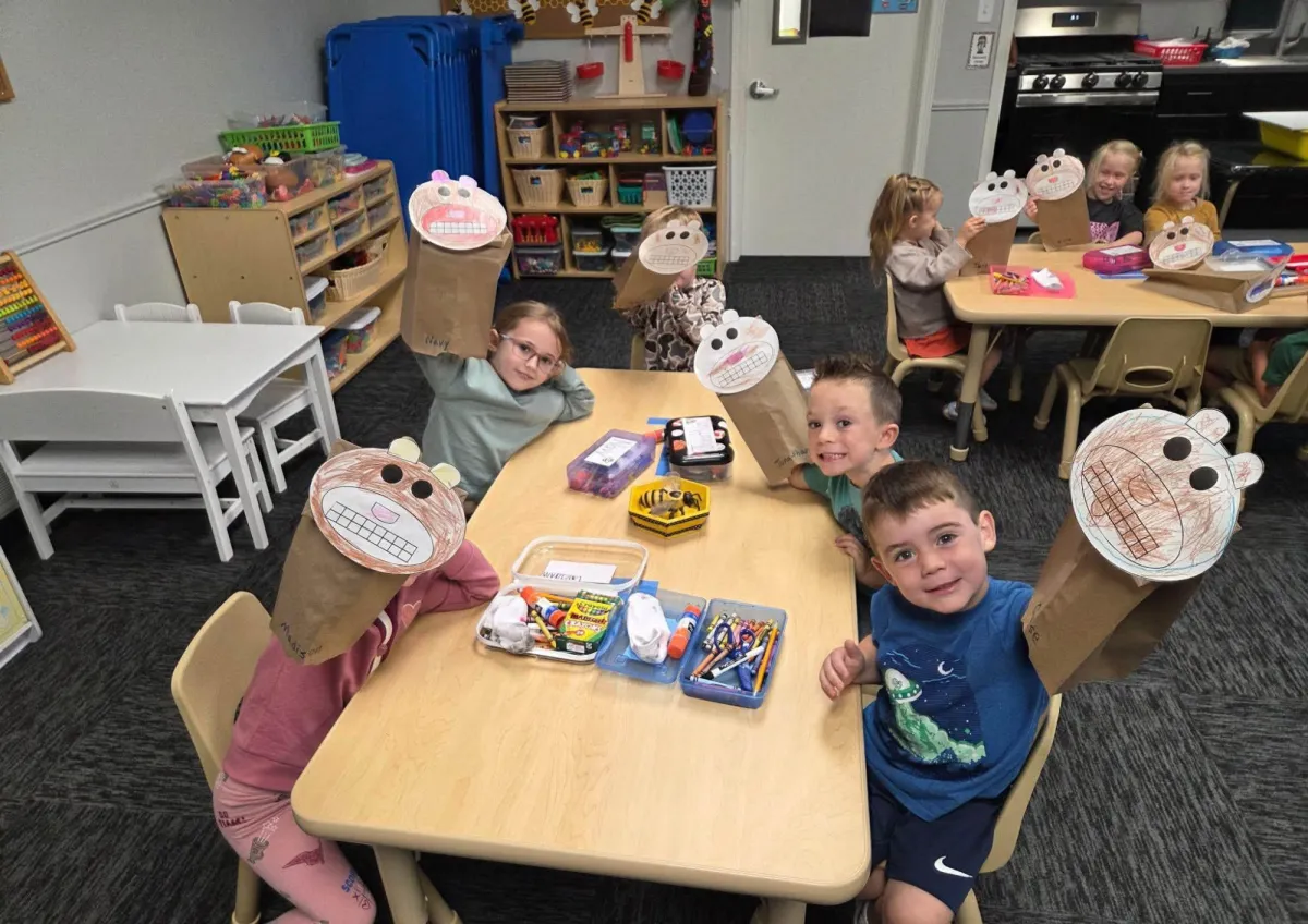 Preschoolers wearing paper-bag dog masks at a classroom table