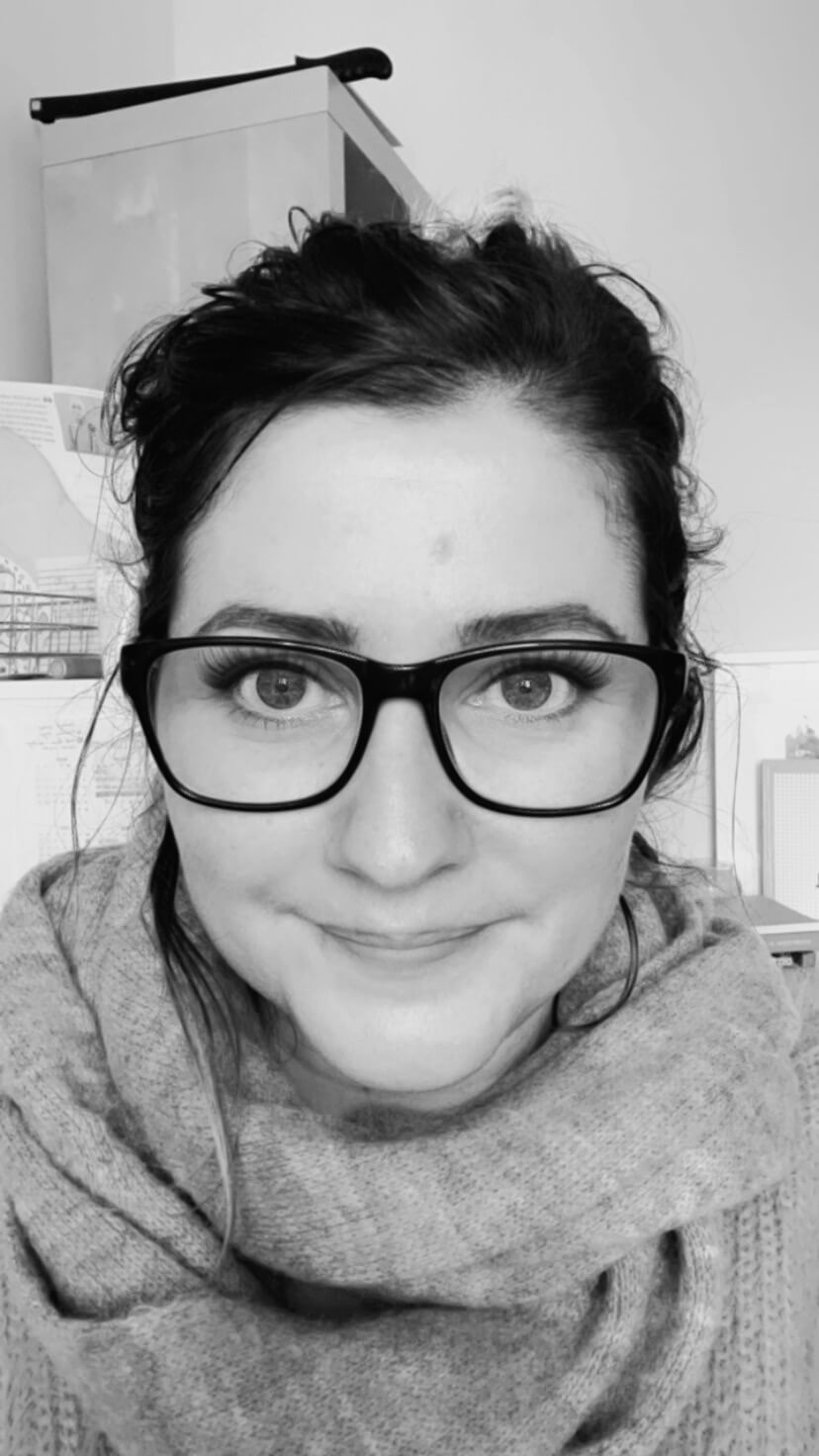 Shelly Terry, founder of Sheldon Social, in a black and white close-up photo wearing glasses and a cosy knit scarf — content strategist and visibility consultant helping founders and brands shape how they're understood online.