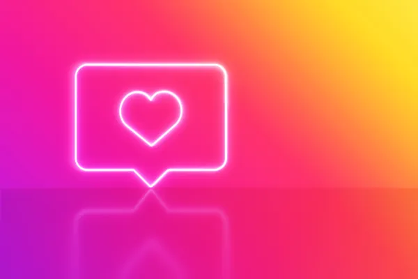 A neon glowing heart notification icon on a vibrant pink and yellow gradient background — a decorative image used to illustrate a Sheldon Social blog post on social media engagement and strategic content systems.