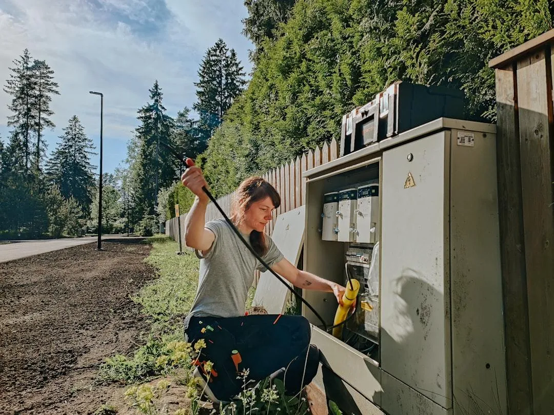 woman adjusting an electrical box attached to fence