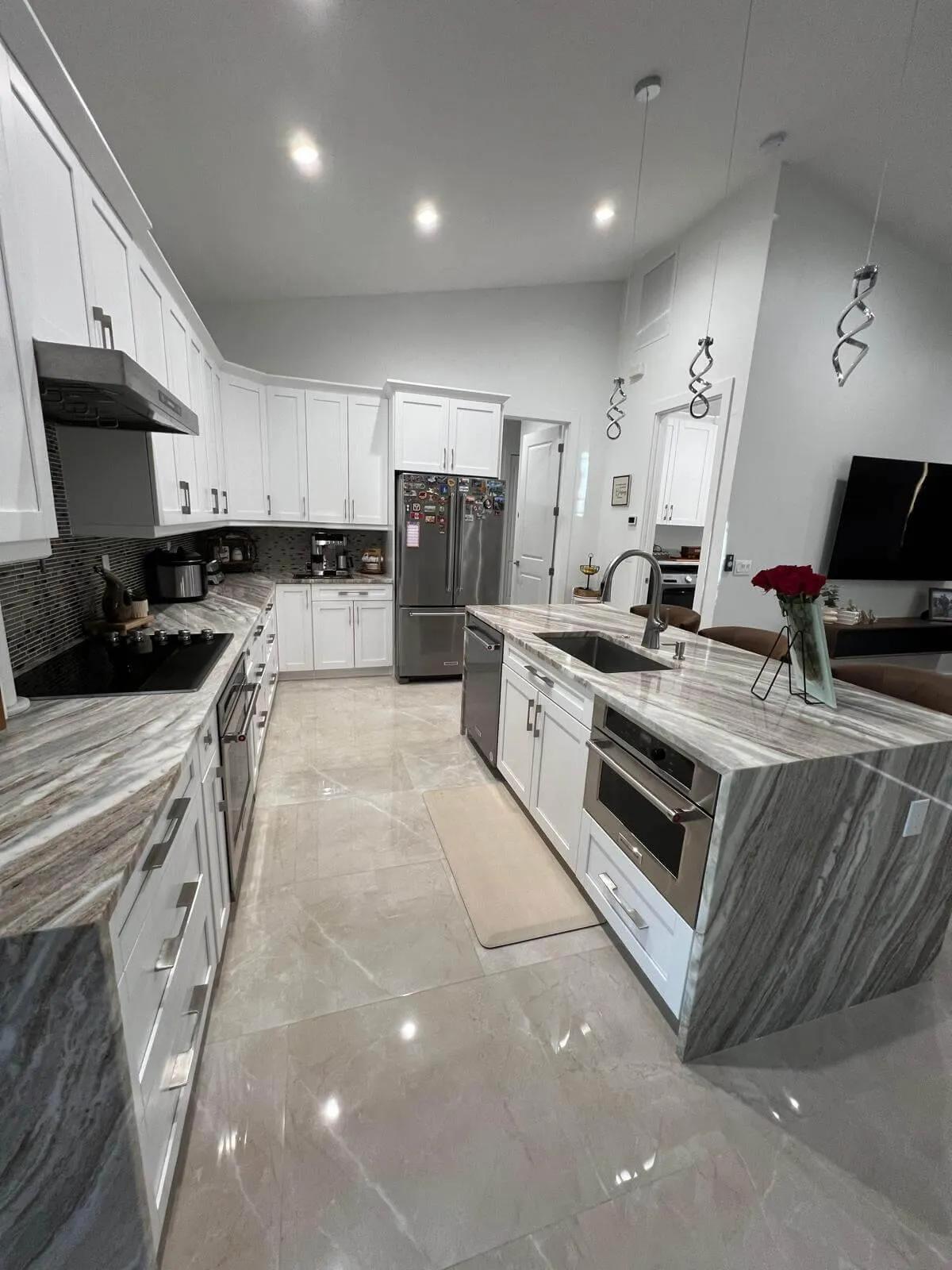 Modern kitchen remodel with white shaker cabinets, sleek stainless steel appliances, marble-look quartz countertops, and a waterfall island design.