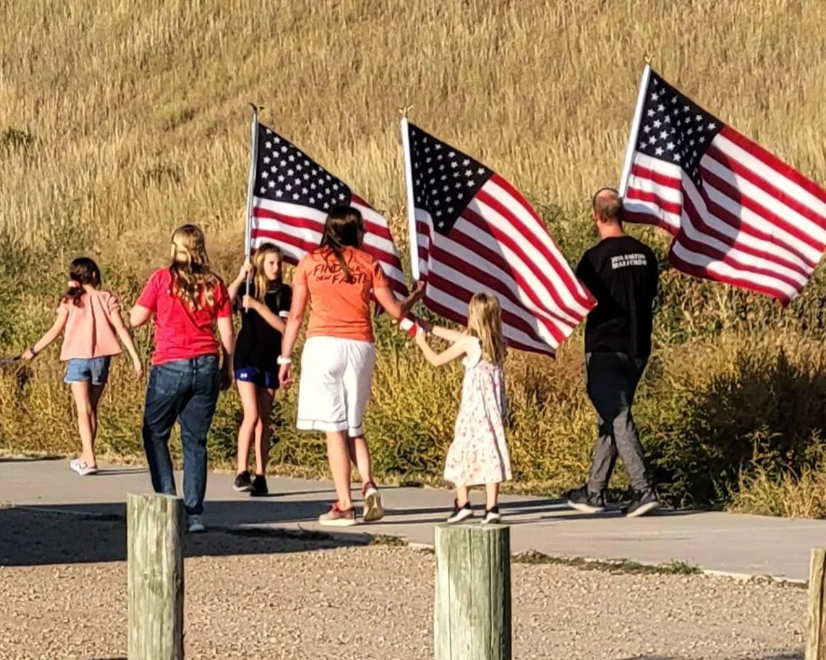 Family and community members carrying American flags at the 9/11 tribute