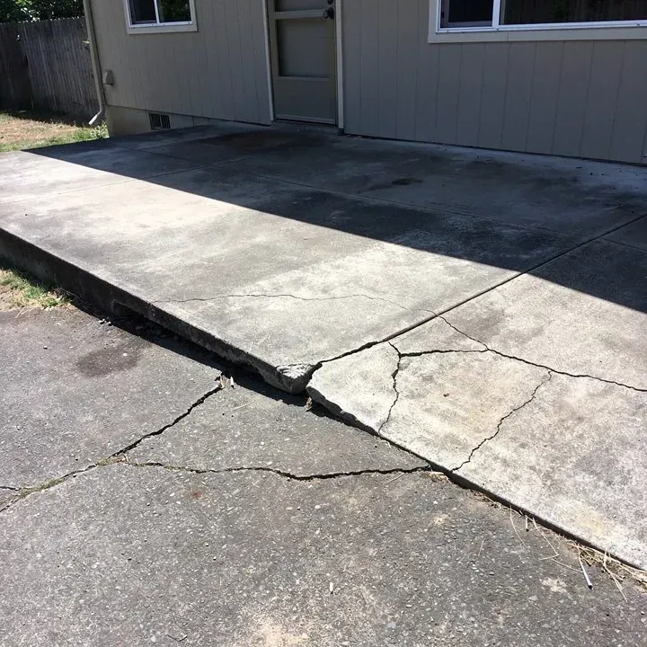 Sunken, cracked section of an aging concrete patio attached to a home in Ashland, Oregon