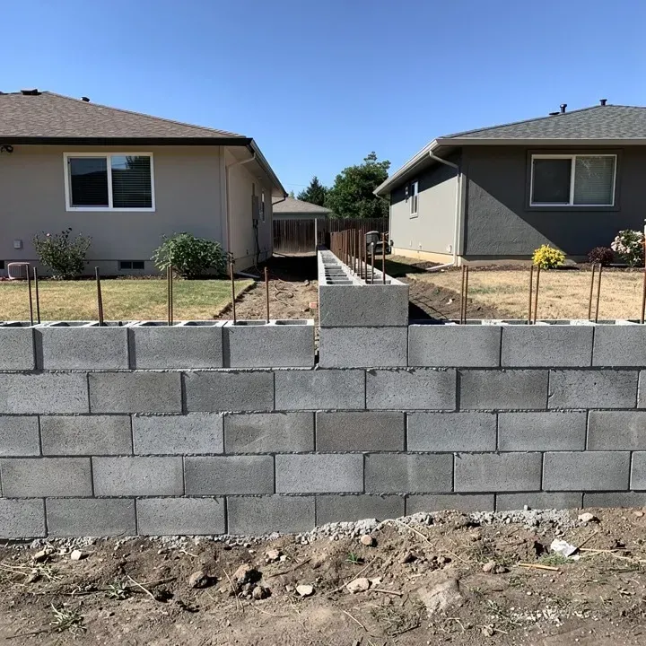 Concrete block wall under construction between two modest homes in Ashland, Oregon