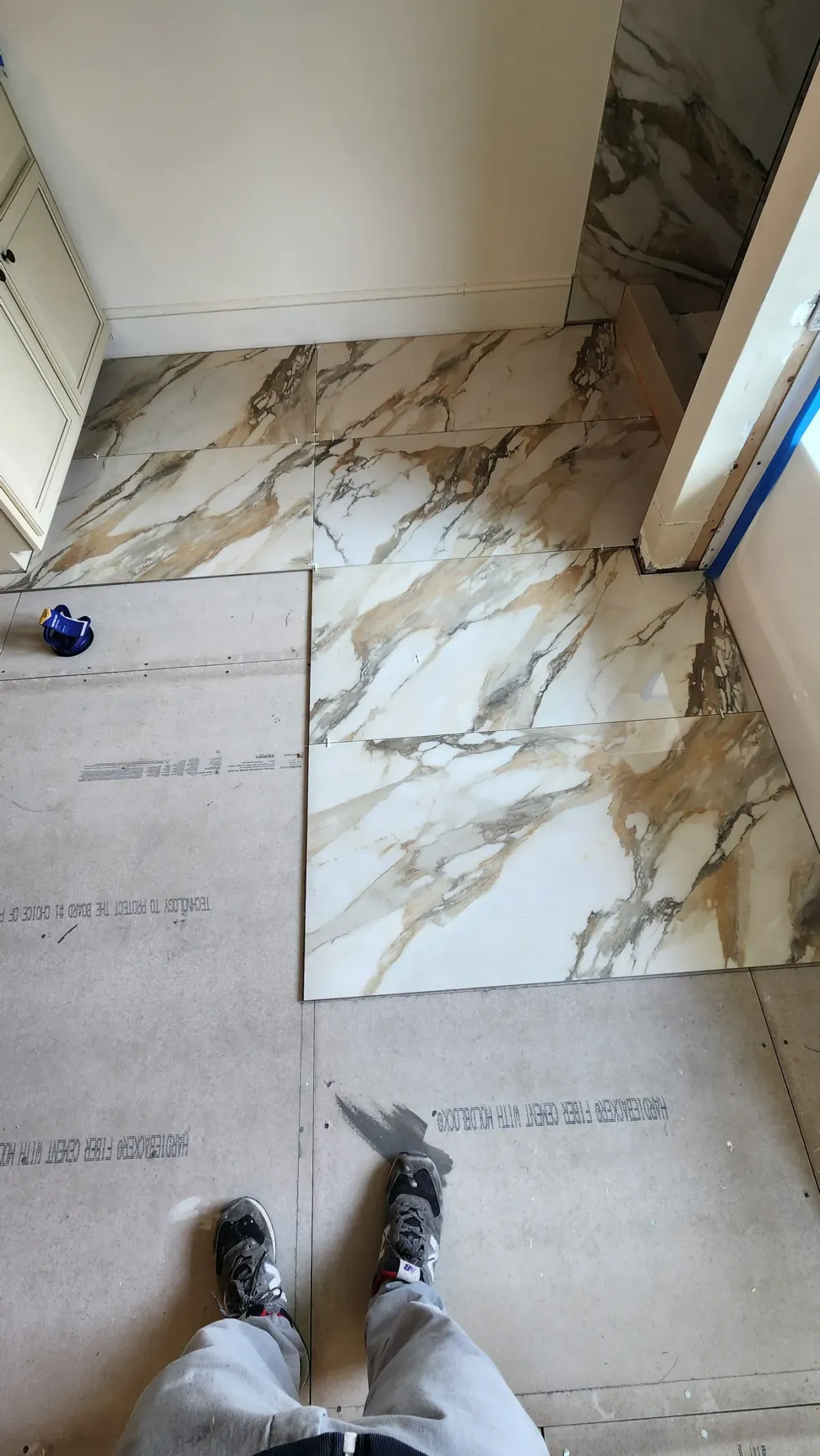 Layout before adhesive. Dry laid and measured so the cuts land where nobody looks, not in the middle of the room