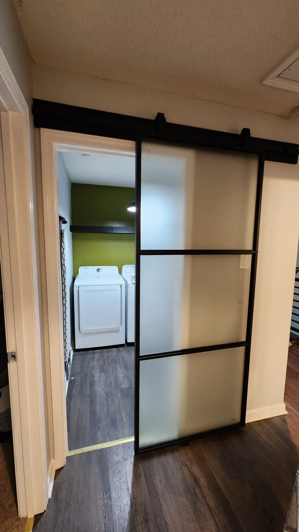 Barn door on a black track. Frosted glass, built from scratch, hung to clear the trim