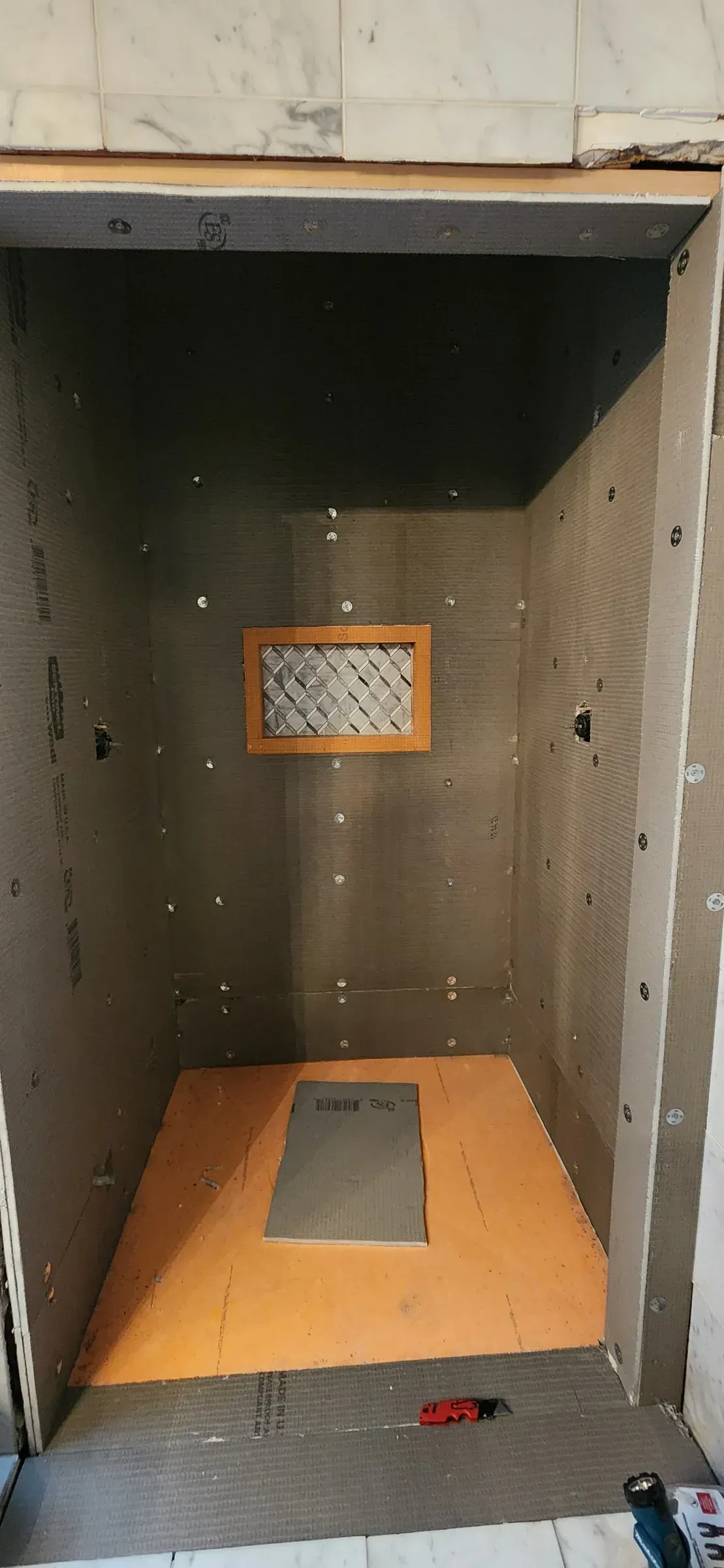 Orange Schluter KERDI waterproofing membrane in a shower
