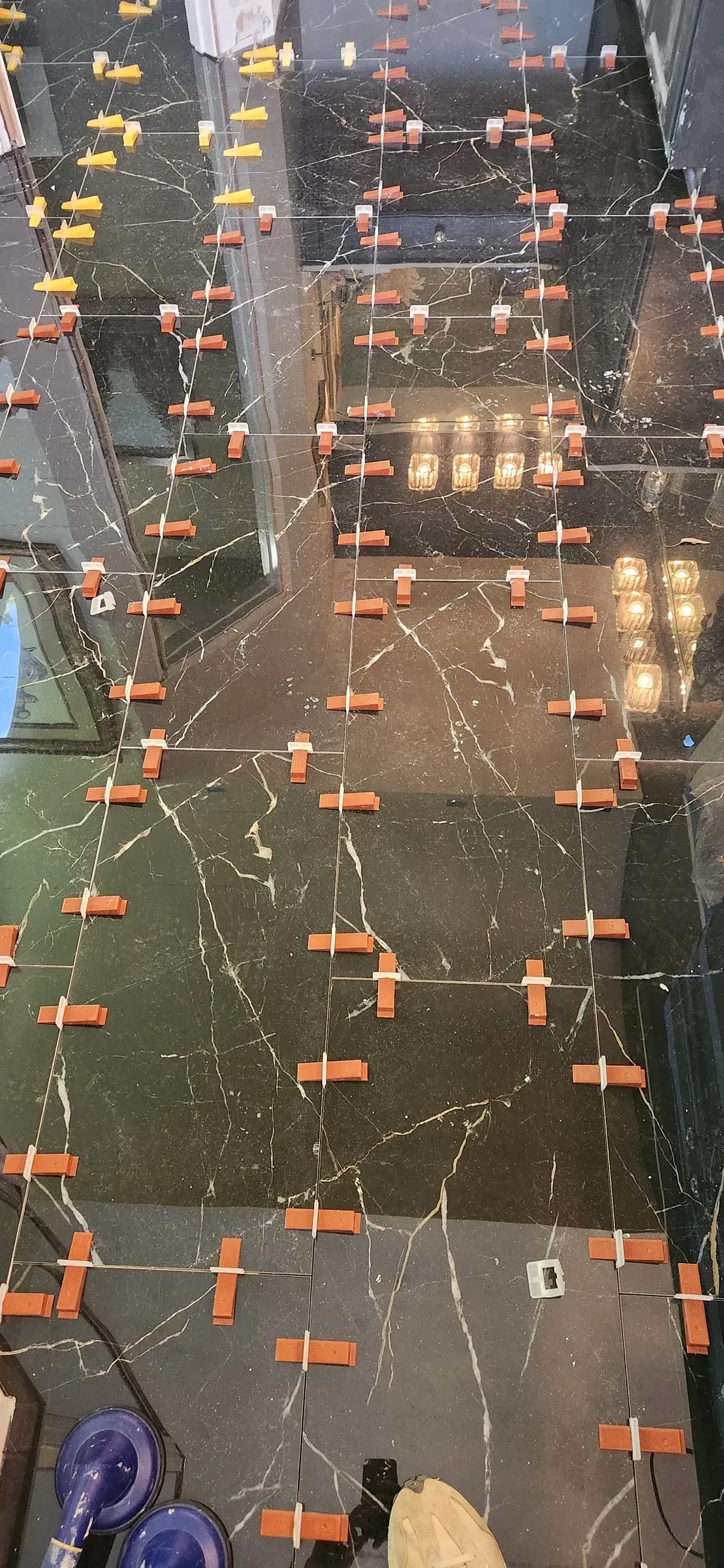 Leveling clips. Every tile held flush to its neighbour while the mortar cures. Slower, more expensive, dead flat