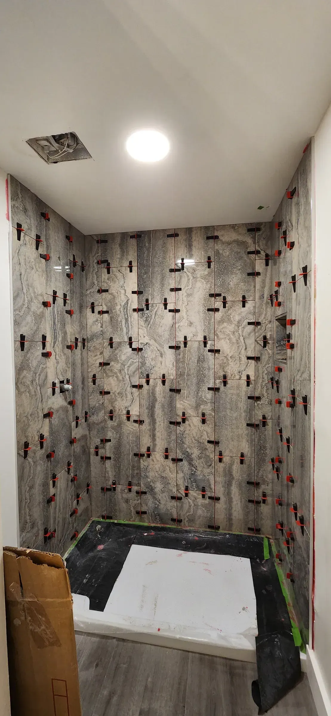 Shower walls set with leveling clips, pan taped and protected
