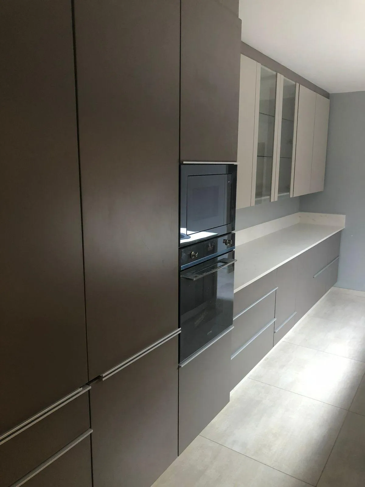 Gray kitchen units with space for microwave and melamine countertops.