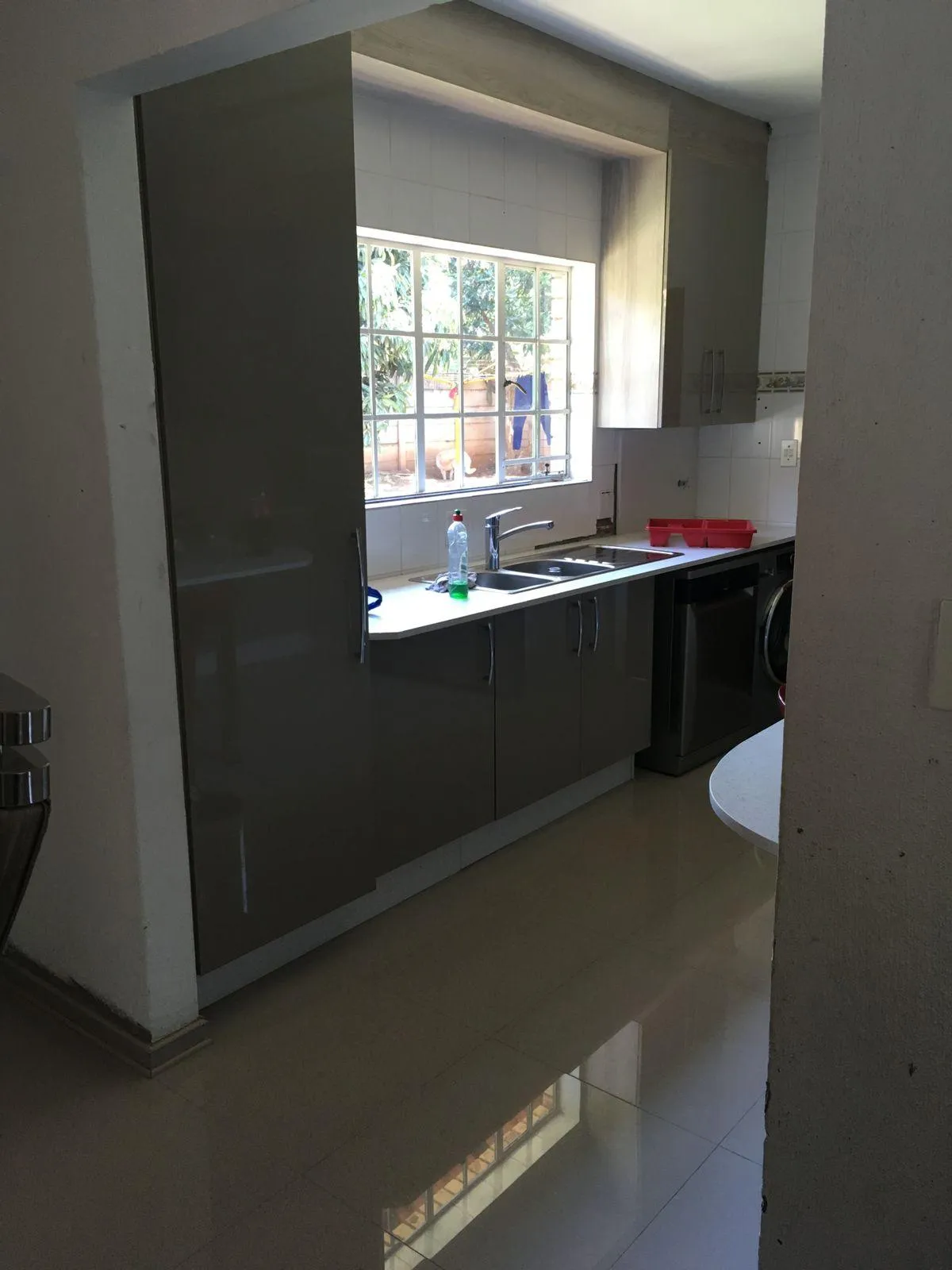 Gray kitchen cabinets with space for microwave and washing machine.