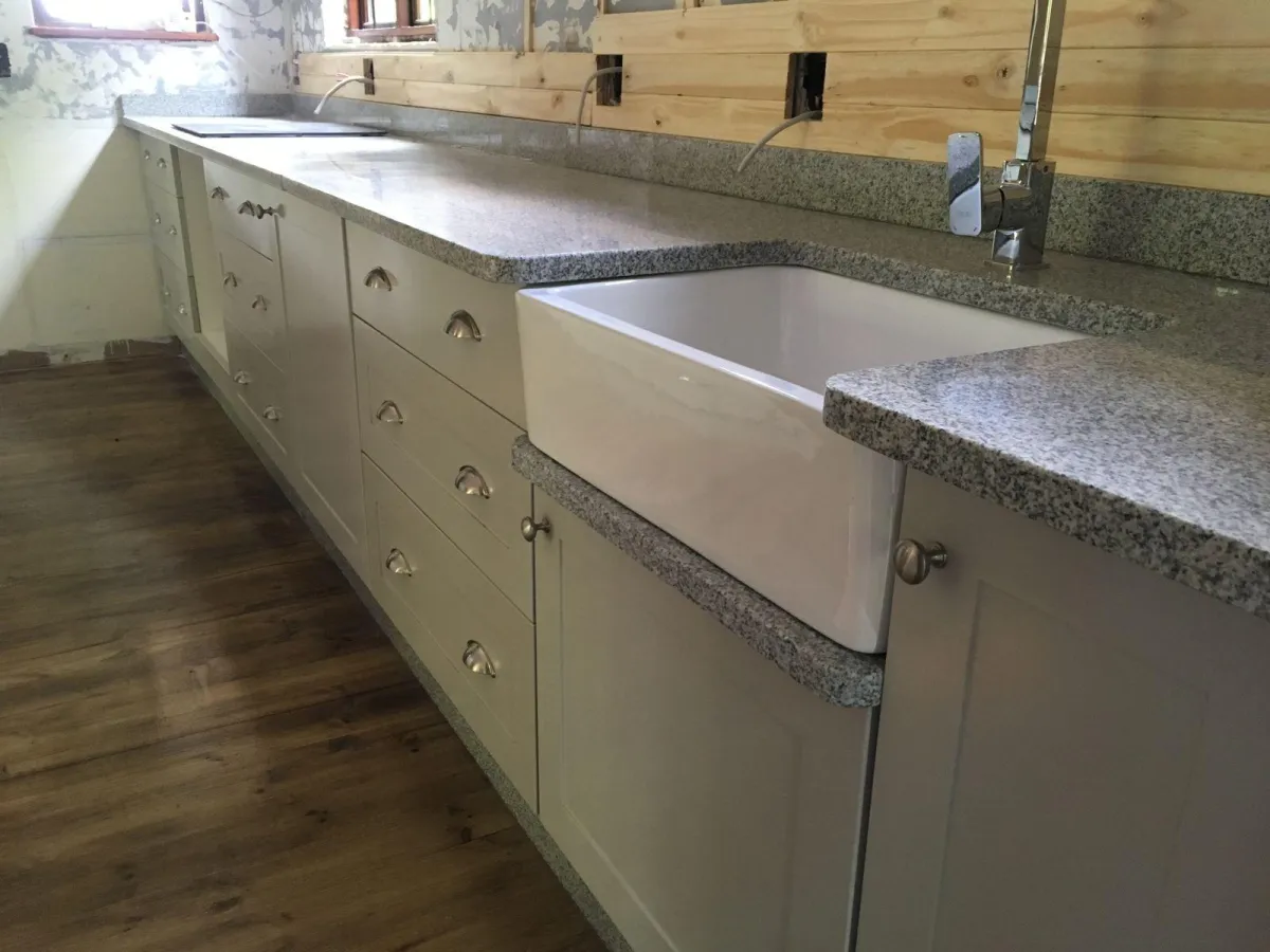 Gray kitchen cupboards with quartz countertops and built-in sink.