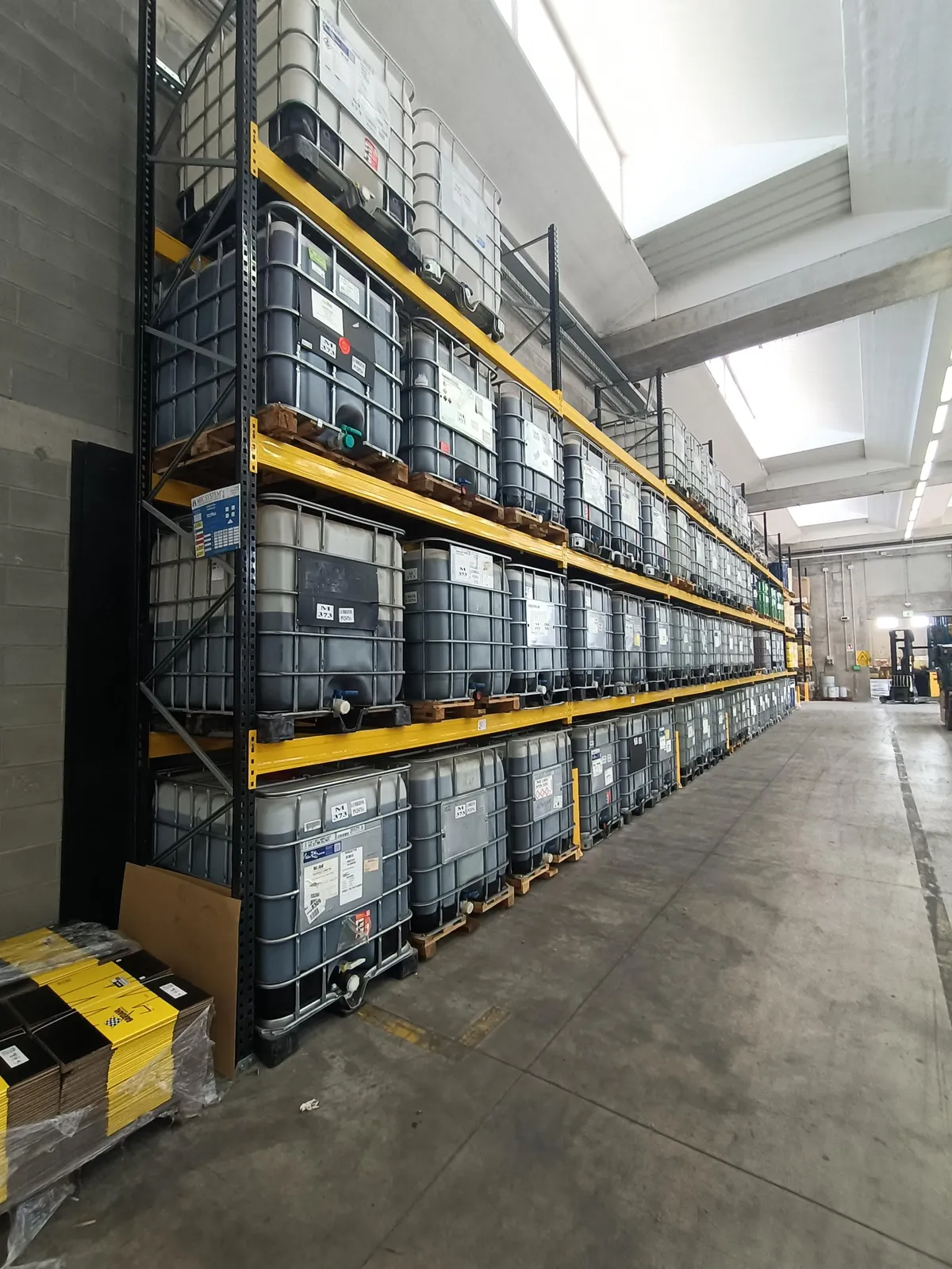 Scaffalatura metallica di magazzino con contenitori IBC, esempio di stoccaggio industriale da controllare periodicamente per la sicurezza