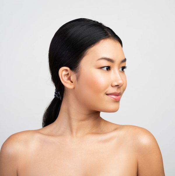 Female dermatologist, 40s, smiling, modern clinic, 1:1 aspect ratio