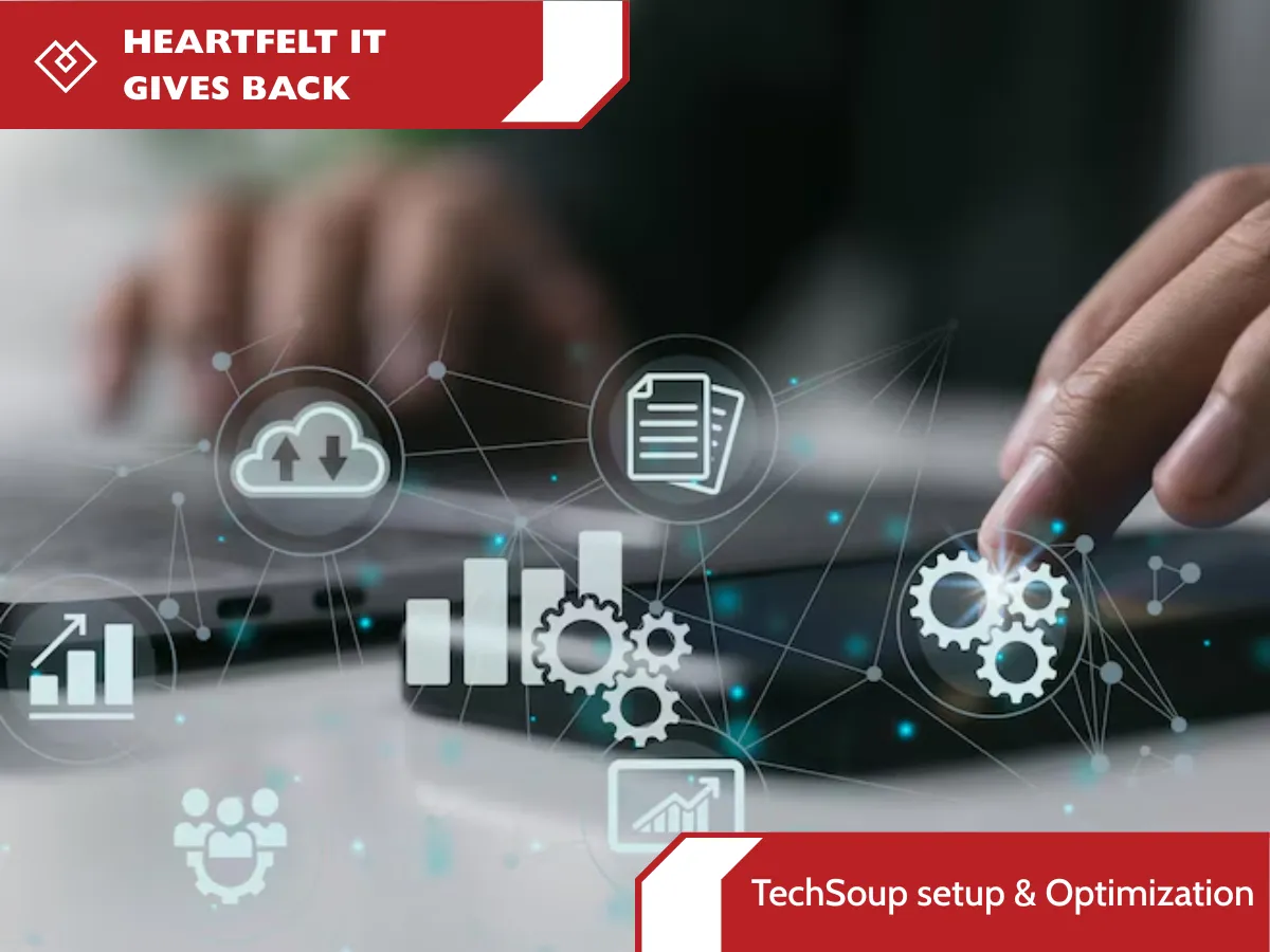 A conceptual marketing image for "HEARTFELT IT GIVES BACK" with a focused view on a person's hands. One hand types on a laptop while the other is near a smartphone, illustrating the "TechSoup Setup & Optimization" process. Both devices are part of a glowing network of connecting lines and data icons, including cloud upload/download, gears, bar charts, and a team of people, emphasizing a modern IT infrastructure. Red and white banners with text are at the top-left and bottom-right corners, respectively.