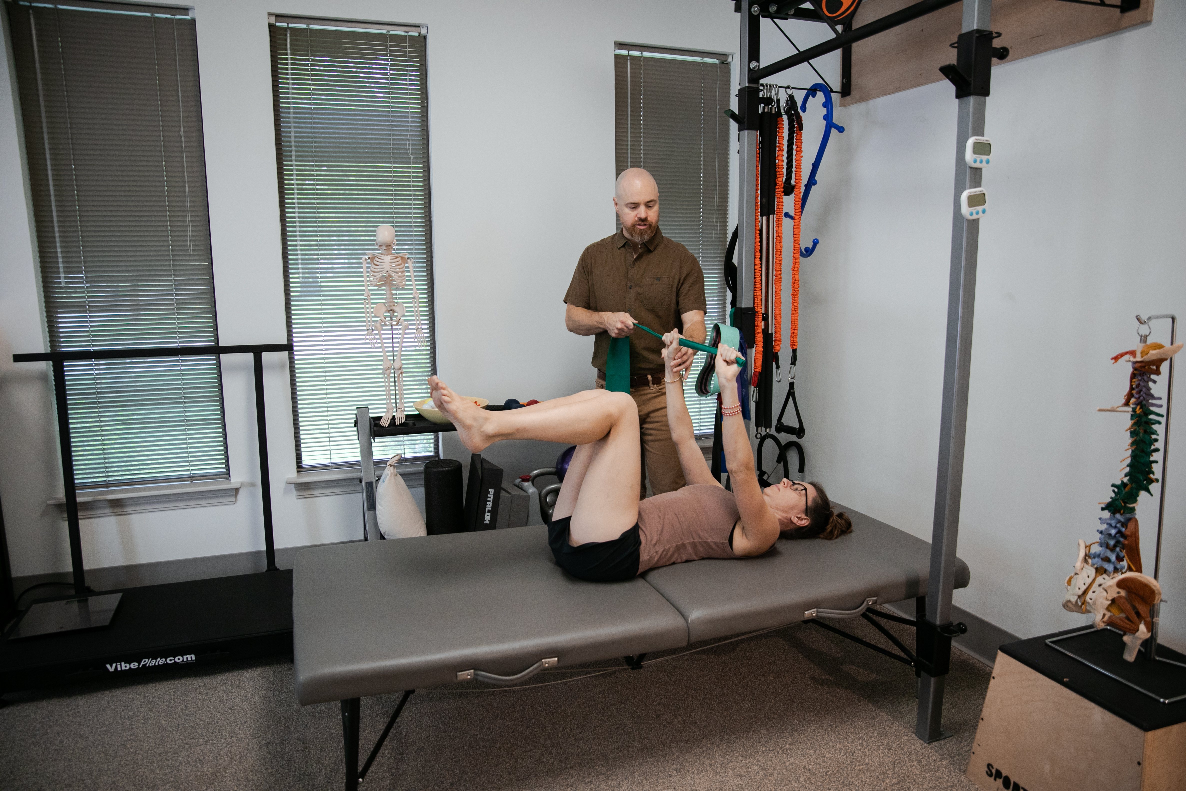 Woman receiving exercise therapy with resistance band from therapist, emphasizing rehabilitation and personalized care at ZOVA Chiropractic Rehab Center.