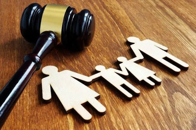 A gavel beside wooden figures of a family being separated, symbolizing a divorce or custody case.